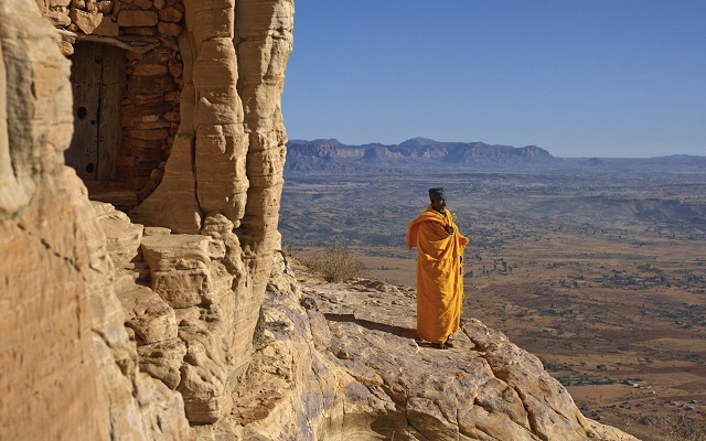 a yellow dressed monk standing on the Tigray gerealta cliff